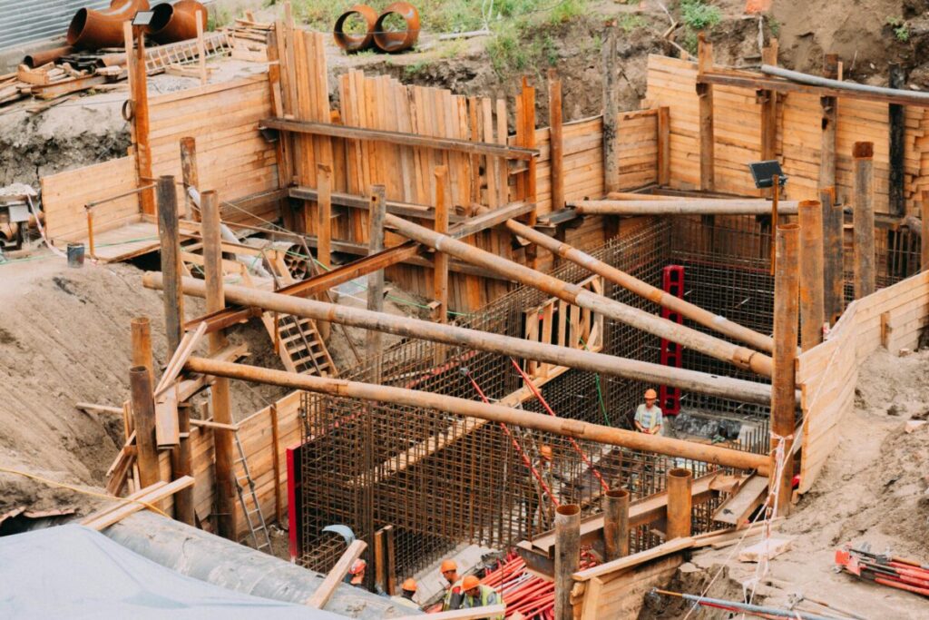 Aerial view of a construction site with workers, wooden framework, and scaffolding.