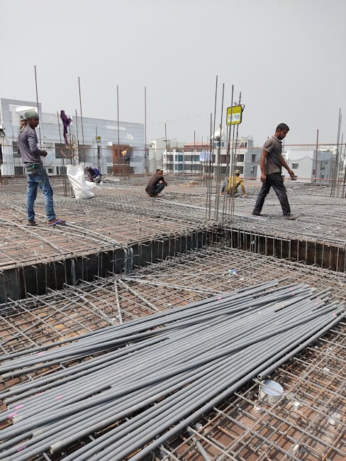 Workers engaged in construction on a building site, laying metal frameworks.